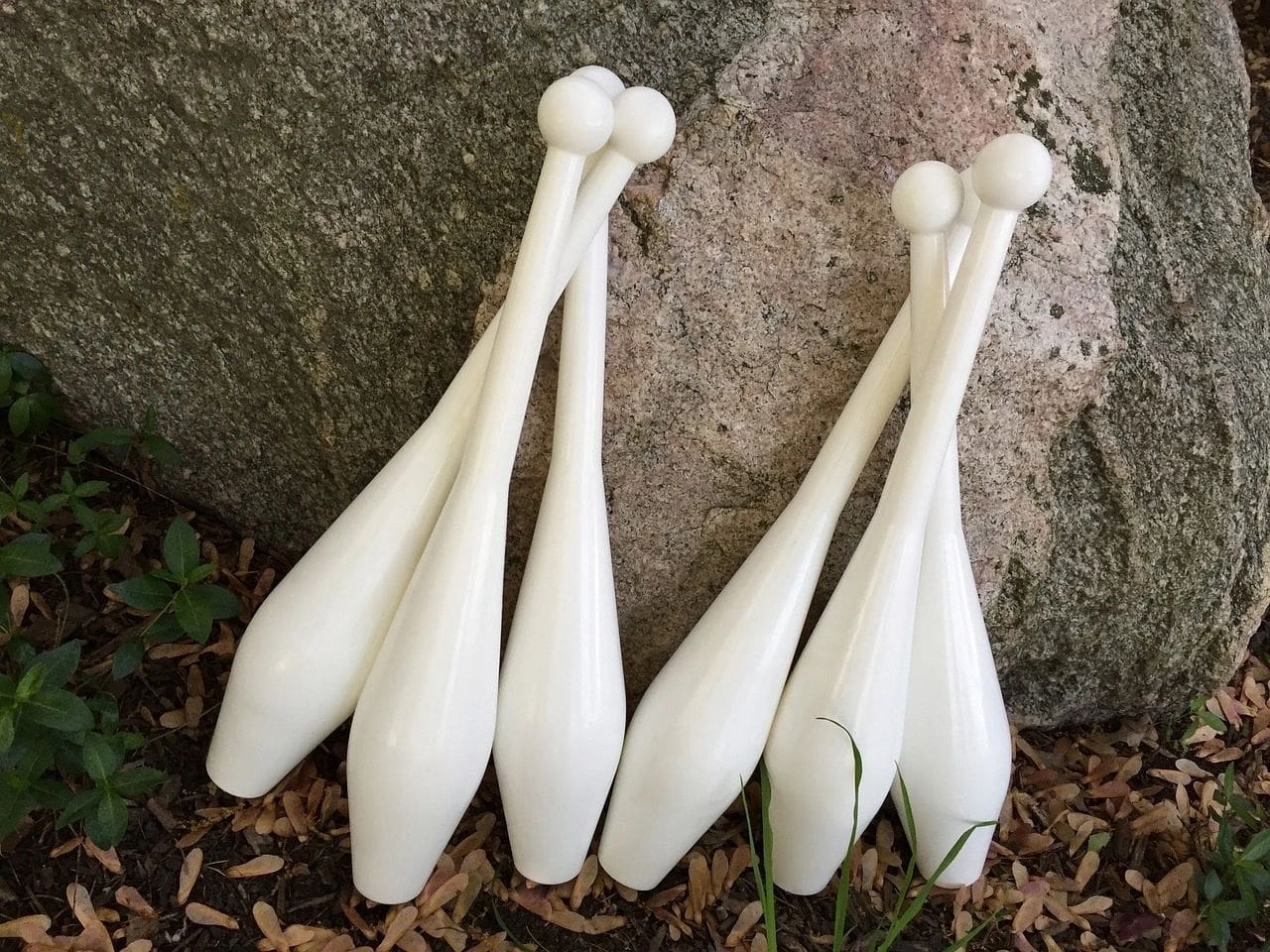 A group of white plastic bats sitting on top of the ground.