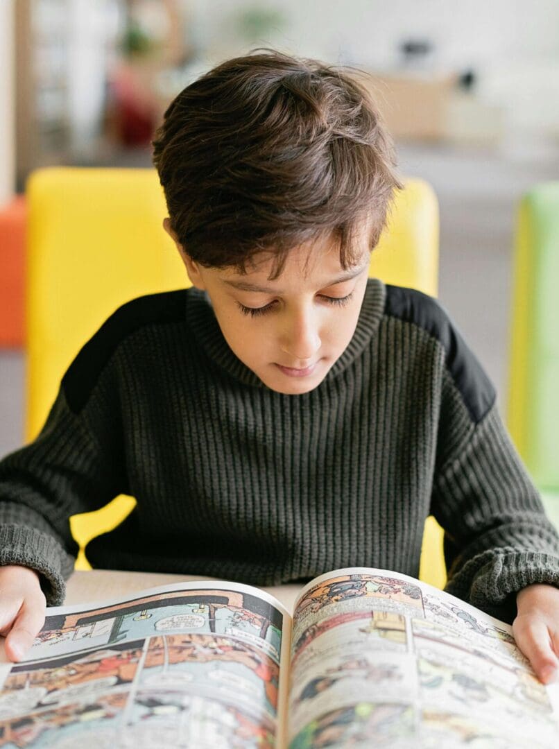 A boy is reading a book in the library.